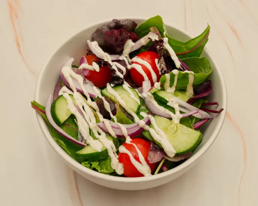 A fresh side salad of leaves, cucumber, tomato and red onion with dressing
